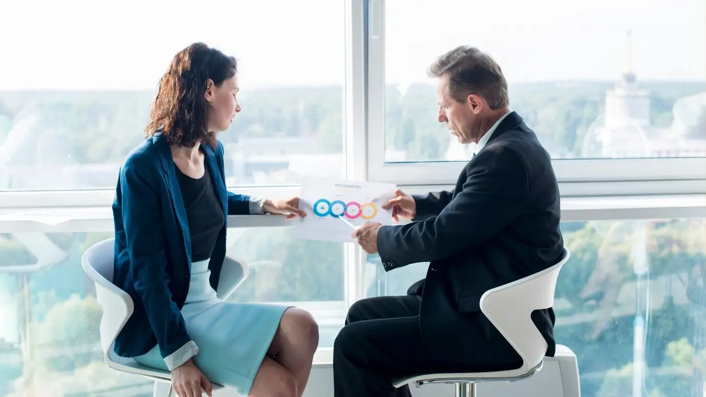 Бизнесмен объясняет своей коллеге-женщине диаграмму.